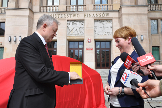 na fotografii  wiceminister Wiesław Janczyk wręcza kluczyki do samochodu pani Beacie przed gmachem Ministerstwa Finansów