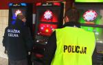 Zdjęcie przedstawia funcjonariusza celno-skarbowego oraz policji i automaty do gry.