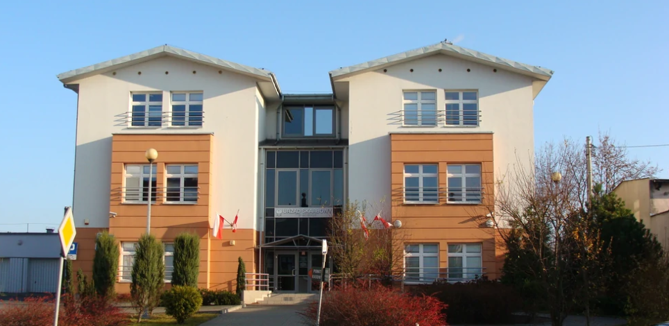 Dwupiętrowy budynek Urzędu Skarbowego w Mogilnie. Przed urzędem drzewa i krzewy.