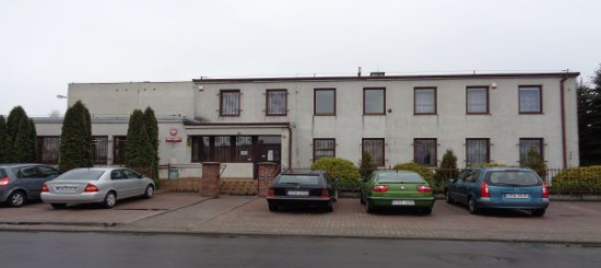 Długi, piętrowy budynek Urzędu Skarbowego w Radziejowie. Przed budynkiem zaparkowane samochody.