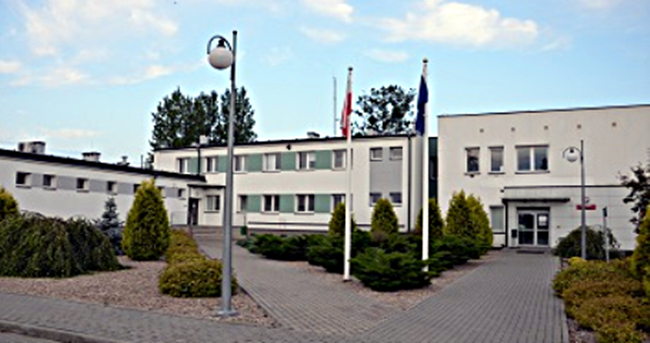 Jednopiętrowe budynki Kujawsko-Pomorskiego Urzędu Celno-Skarbowego w Toruniu. Przed budynkami chodnik i zieleń.