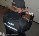 Funkcjonariusz KAS trzymający paczki z papierosami