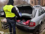 Funkcjonariusz KAS stoi przy otwartym bagażniku samochodu osobowego, w którym schowane są zatrzymane towary