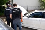 Funkcjonariusz Służby Celno-Skarbowej i funkcjonariusz niemieckiej policji stoją tyłem przy samochodzie, który ma otwartą maskę.
