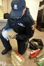 Funkcjonariusz Służby Celno-Skarbowej trzyma w ręku worki z tytoniem