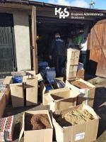 Przed garażem stoją kartony wypełnione paczkami papierosów i tytoniem.