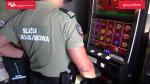 Funkcjonariusze stoją przed automatem do gier hazardowych.