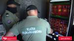 Funkcjonariusze stoją przed automatem do gier hazardowych i przeprowadzają eksperyment.
