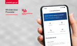 Dłoń  trzymająca telefon komórkowy na którym uruchomiona jest aplikacja mobilna.