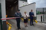 Trzy osoby przygotowują się do przecięcia czerwonej wstęgi.