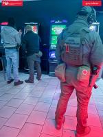 Funkcjonariusze SCS stoją w pomieszczeniu z automatami do gier hazardowych.